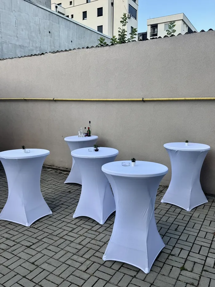 Beli koktel stolovi sa flašama i čašama na popločanoj terasi