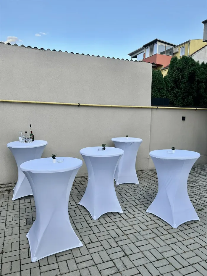 Beli barski stolovi sa posluženjem na terasi pred početak proslave